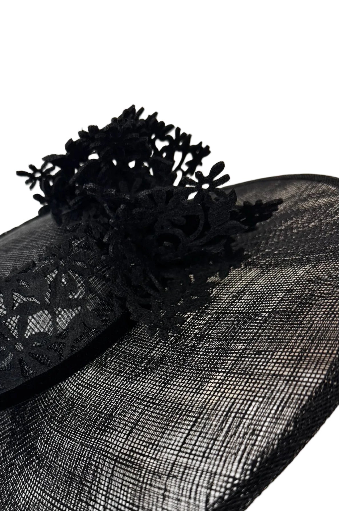 Black lace hat with floral details on a mannequin head against a white background