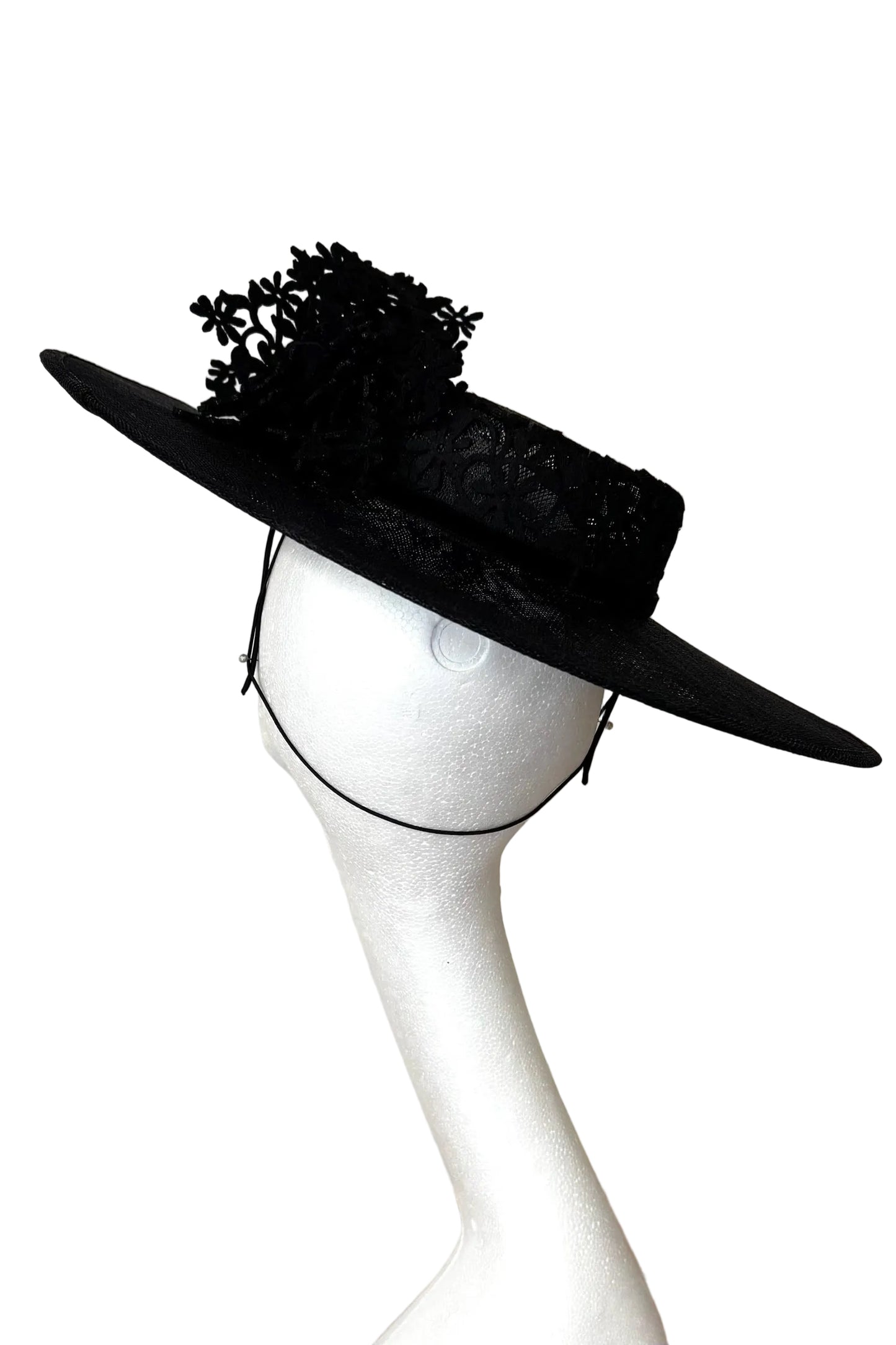 Black wide-brimmed hat with decorative elements on a mannequin head against a white background