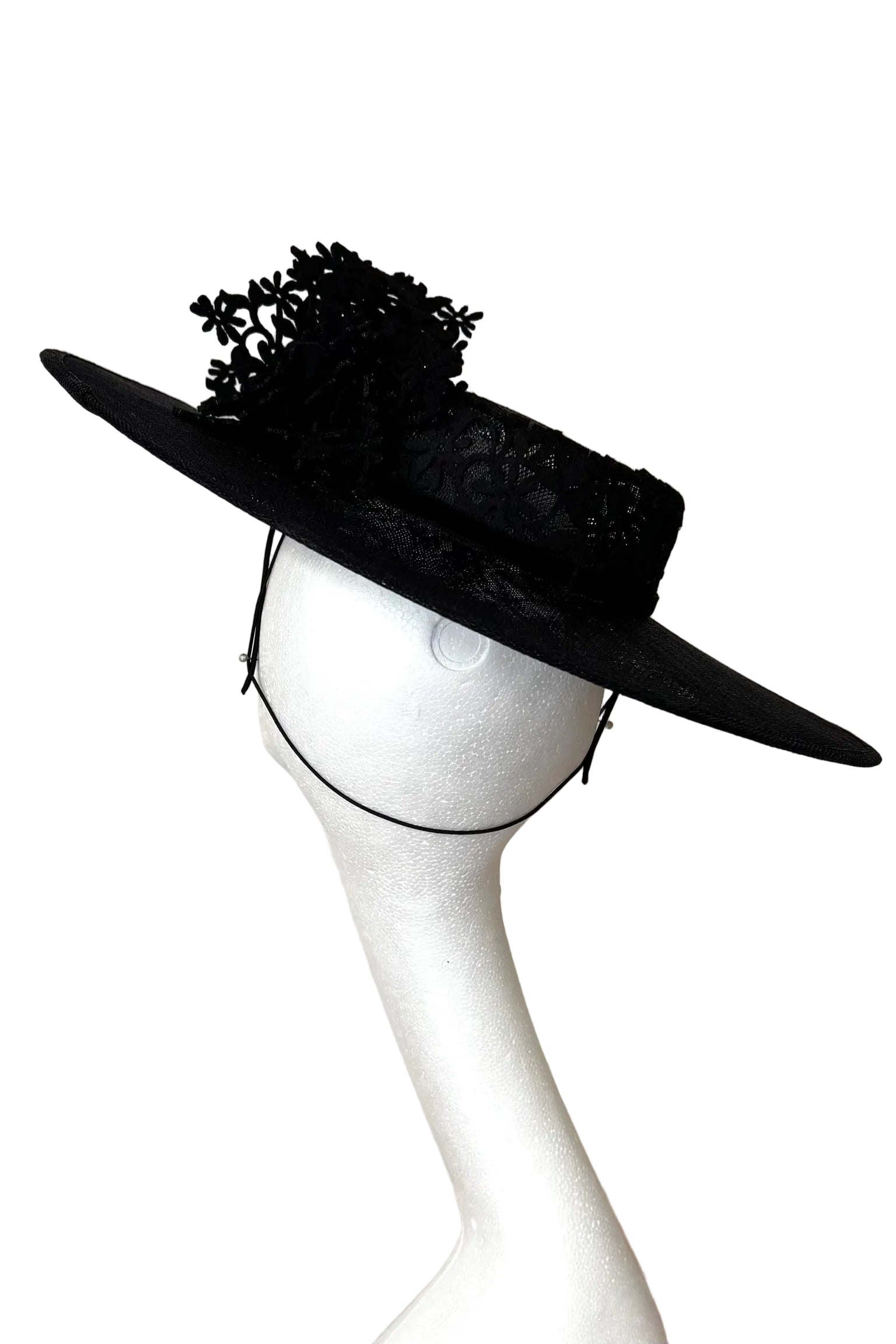 Black wide-brimmed hat with decorative elements on a mannequin head against a white background