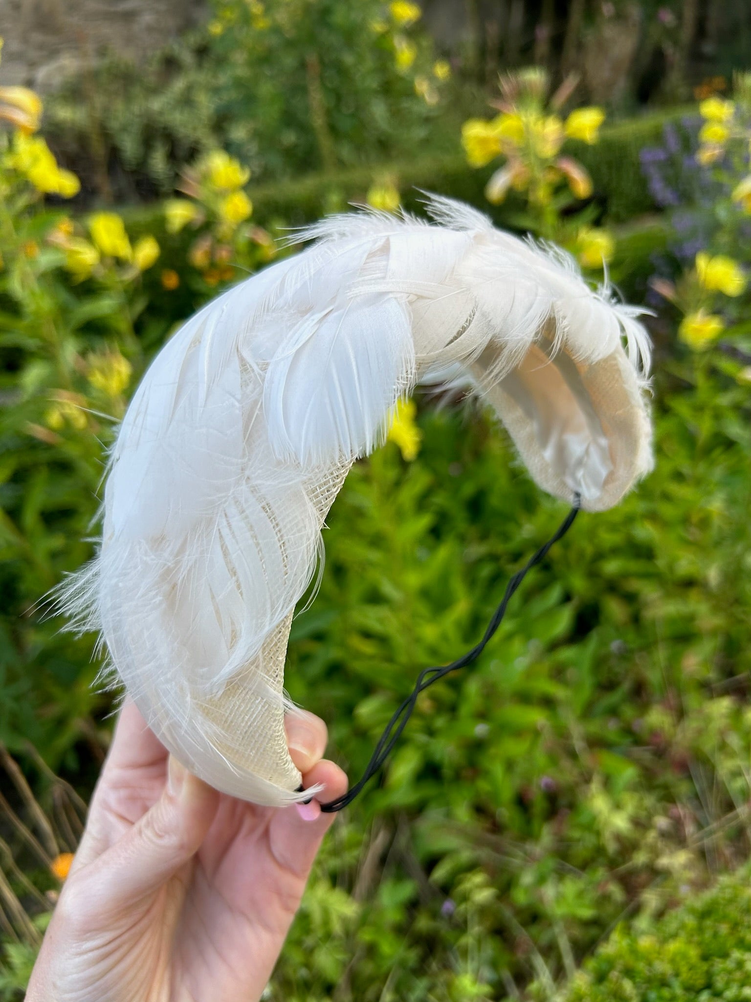 White feather held in a hand with a blurred natural background