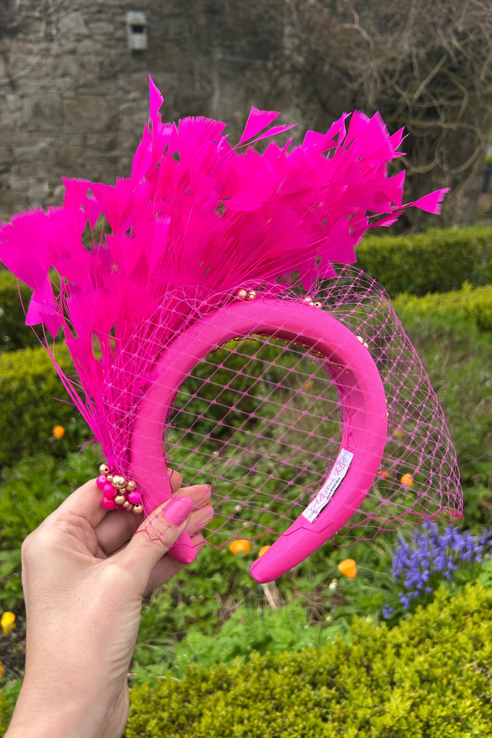 Magenta headband with veiling and feathers for hire