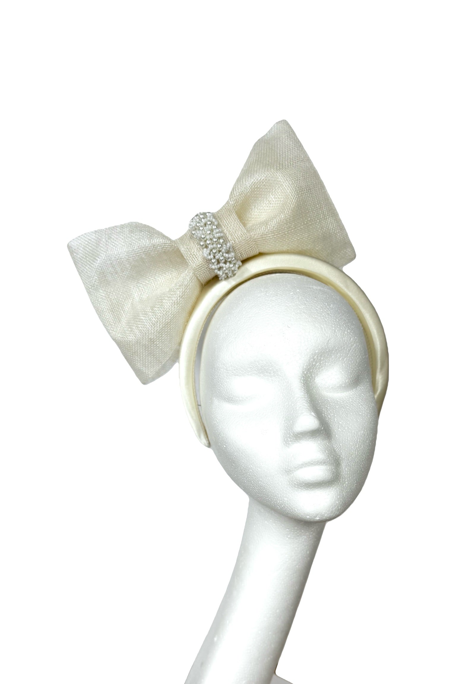 White headband with bow and embellishments on a mannequin head against a white background