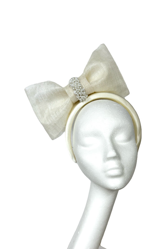 White headband with bow and embellishments on a mannequin head against a white background